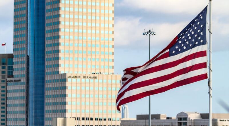memorial hermann tower and an america flag
